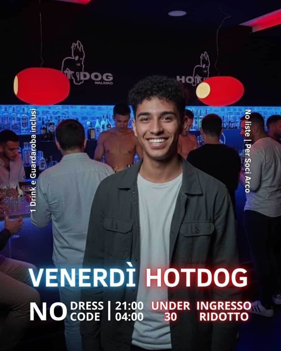 Giovane uomo sorridente in un bar gay con luci rosse e sfondo di clienti.