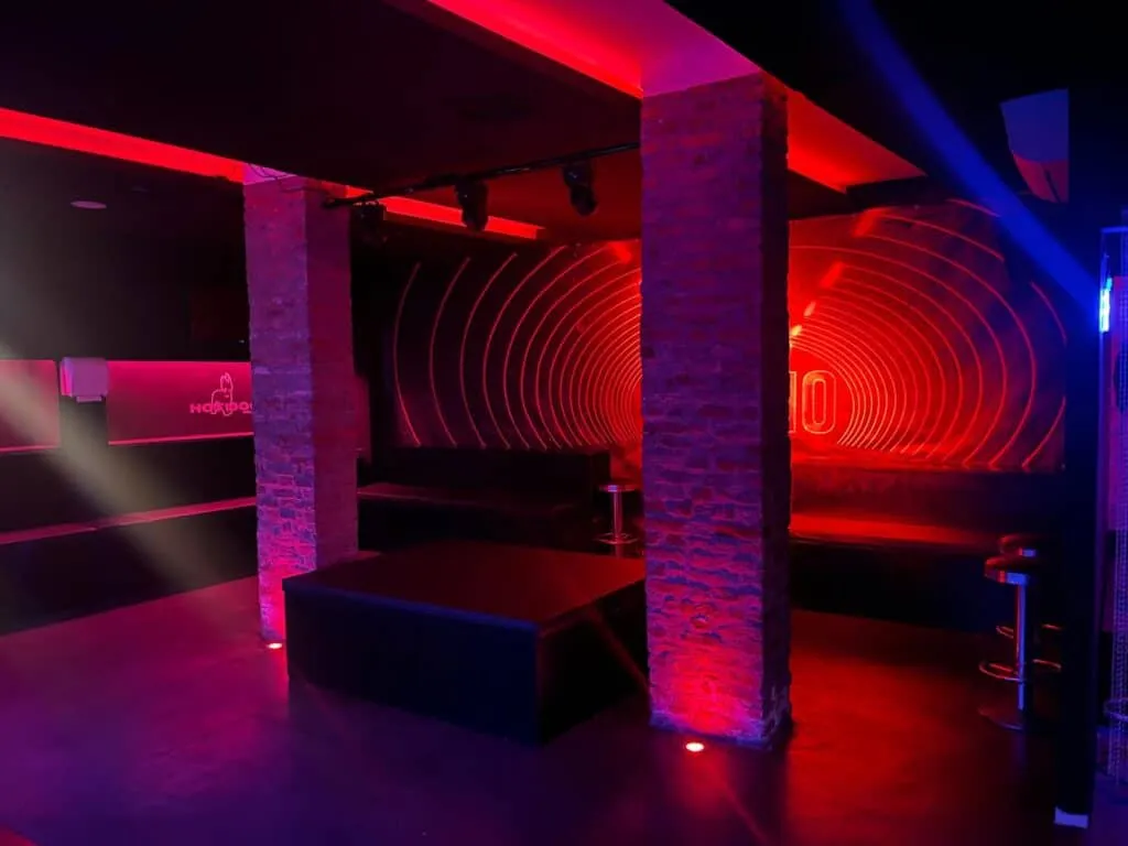Atmosfera moderna con luci rosa e rosse, perfetta per serate gay di socializzazione e divertimento.
